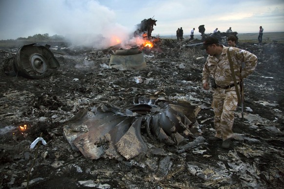FILE - People walk amongst the debris at the crash site of a passenger plane near the village of Grabovo, Ukraine, July 17, 2014. An international team is presenting an update Wednesday Feb. 8, 2023 o ...