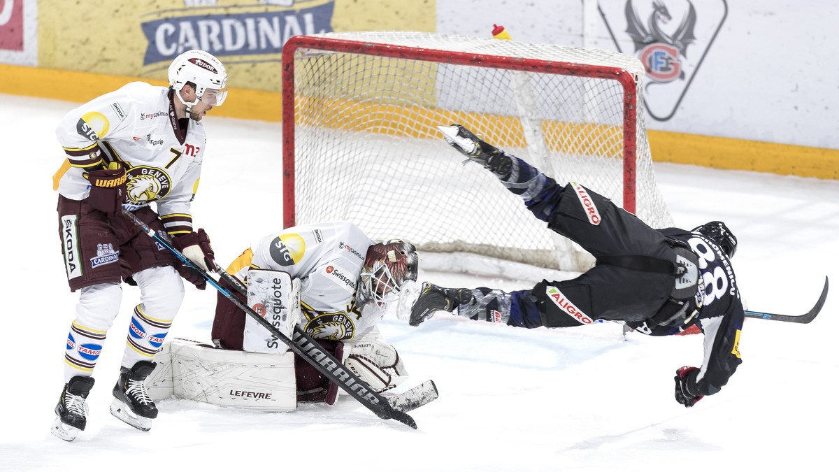 Le defenseur genevois Henrik Toemmernes, gauche, et le gardien genevois Gauthier Descloux, centre, luttent pour le puck avec l'attaquant fribourgeois Christopher DiDomenico, droite, lors du match ...