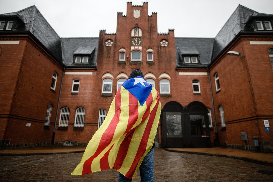 epaselect epa06640131 Catalan sympathizer Eduardo Alonso has a Catalonian Independence flag wrapped around his shoulders as he waits in front of the &#039;Justizvollzugsanstalt (JVA) Neumuenster&#039; ...
