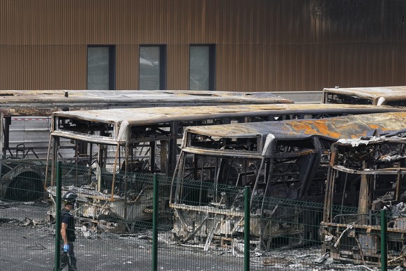 A police investigator watches charred buses on a third night of unrest, Friday, June 30, 2023 at the bus depot of Aubervilliers, outside Paris. A dozen of buses have been destroyed. Protesters erected ...