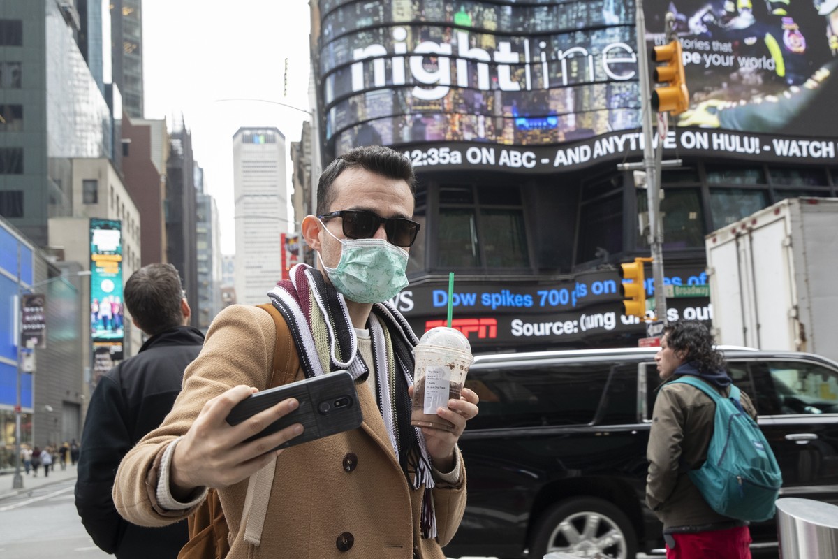 Justin Dalipi, of Albania, wears a mask as a precaution against the Corona virus during the final days of his visit to New York, as he takes a selfie in New York's Times Square, Tuesday, March 10 ...