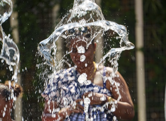 KEYPIX - 13.08.2025, Hessen, Frankfurt/Main: Eine Frau steht hinter einer Wasserfont