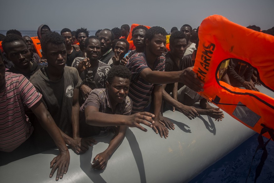 Migrants and refugees receive lifejackets from Spanish NGO Proactiva Open Arms workers, after being located sailing on an out of control rubber boat in the Mediterranean Sea, about 12 miles north of S ...