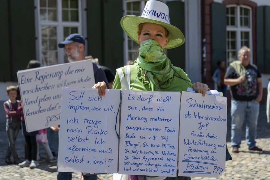 Eine Frau haelt Plakate in die Kamera an einer Mahnwache fuer die Wahrheitsfindung und die Einhaltung der Grundrechte der Organisation Baselwach findet auf dem Marktplatz statt, in Basel, am Samstag,  ...