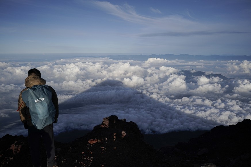 FILE - The shadow of Mount Fuji is cast on clouds hanging below the summit Aug. 27, 2019, in Japan. Three bodies were found inside a crater at the summit of Mount Fuji, Japan?s most famous mountain, w ...