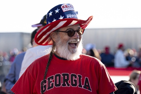 RETRANSMISSION TO CORRECT SPELLING OF PURDUE TO PERDUE - Jesse Johnson of Rex, Ga., waits for the start of a rally featuring President Donald Trump for U.S. Senators Kelly Loeffler, R-Ga., and David P ...