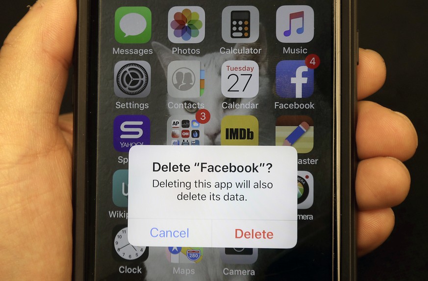 FILE - In this March 27, 2018, file photo, a reporter holds a phone showing the Facebook app in San Francisco. It might not seem like a big deal to have long-forgotten accounts on social media linger. ...
