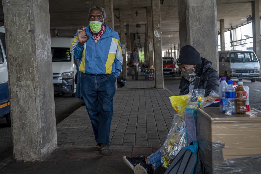 A woman selling snacks, sits at the Baragwanath taxi rank in Soweto, South Africa, Thursday Dec. 2, 2021. South Africa launched an accelerated vaccination campaign to combat a dramatic rise in confirm ...