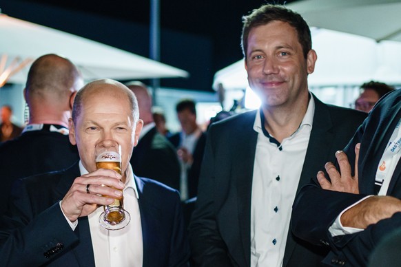 epa09464483 German Minister of Finance and Social Democratic Party (SPD) top candidate for the federal elections Olaf Scholz (L) has a beer with Secretary General Lars Klingbeil (R) after the ARD/ZDF  ...