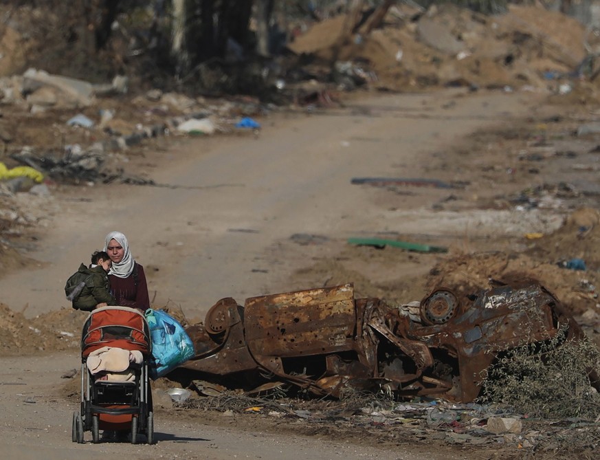 epaselect epa11001314 A Palestinian woman carrying a child walks after crossing from the northern Gaza Strip to the southern Gaza Strip along Salah Al Din road in the central Gaza Strip, 29 November 2 ...