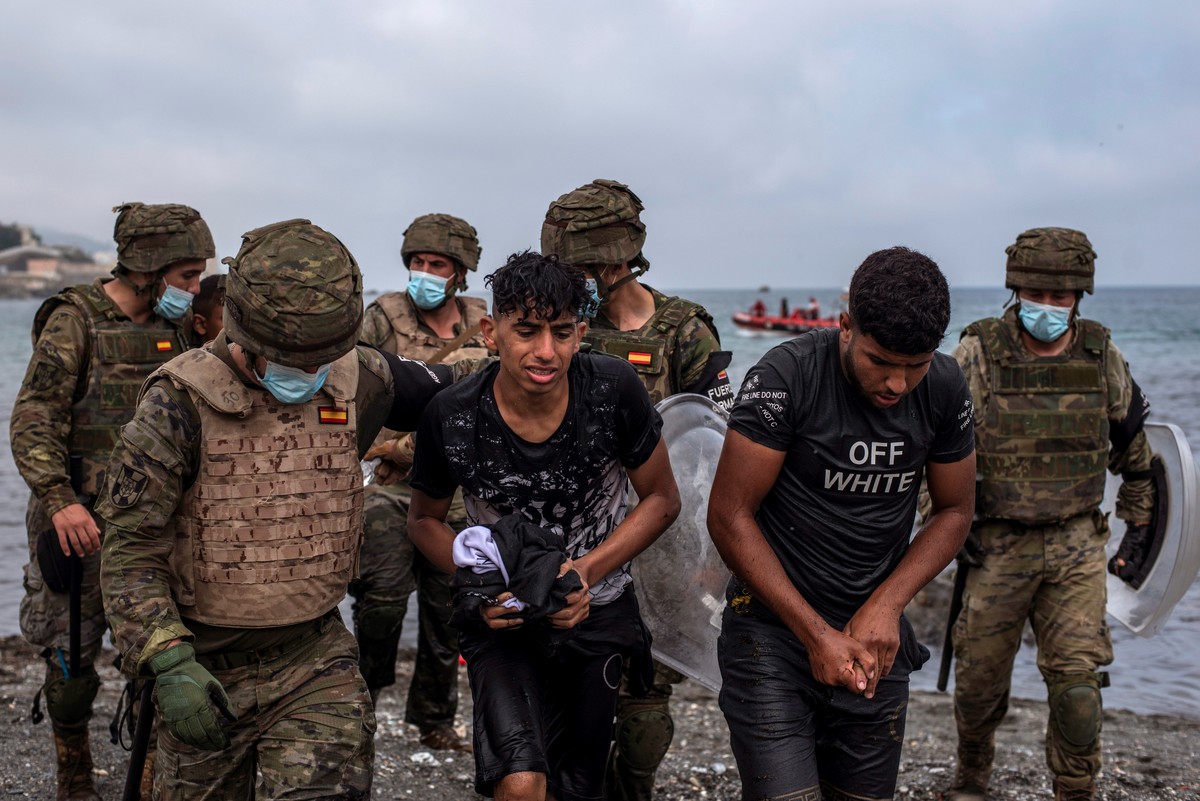 epa09213296 Spanish soldiers help migrants at their arrival at El Tarajal beach, in Ceuta, Spain, 19 May 2021. Spain's Government considers that the massive arrival of some 8,000 irregular migran ...