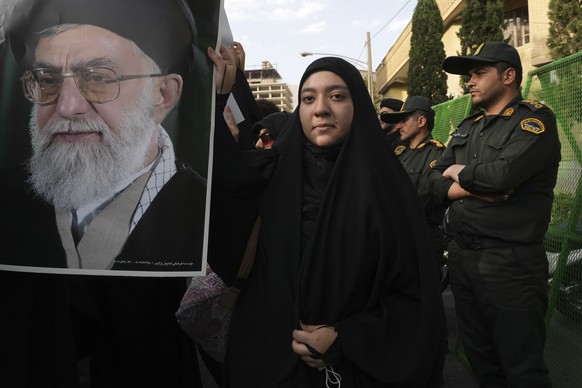 A protester holds a portrait of the Iranian Supreme Leader Ayatollah Ali Khamenei during a protest against Sweden in front of the Swedish Embassy as police officers stand guard, in Tehran, Iran, Frida ...