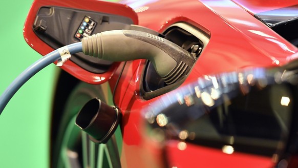 In this Nov. 25, 2016 photo a BMW I8 electric car is connected for power at the Motor Show 2016 in Essen, Germany. The top German automakers, BMW, Daimler, Ford and the Volkswagen Group, and Ford said ...