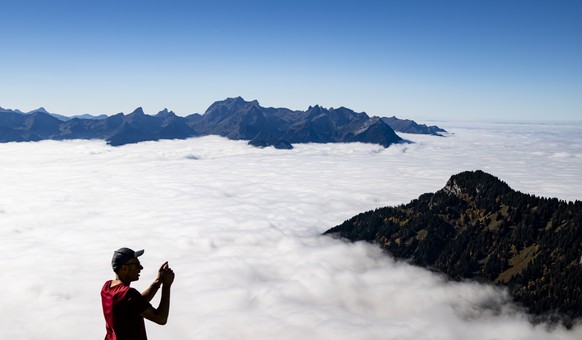 KEYPIX - Une personne prend une photo avec son smartphone de la mer de brouillard qui recouvre la plaine du Chablais et le lac Leman le mardi 14 octobre 2025 depuis de la Berneuse a Leysin dans les al ...