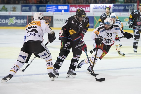 Luganos Stuermer Sebastien Reuille, links, Fribourgs Greg Mauldin, Mitte, und Luganos Stuermer Giovanni Morini, rechts, kaempfen um den Puck, waehrend dem Eishockey-Qualifikationsspiel der National Le ...