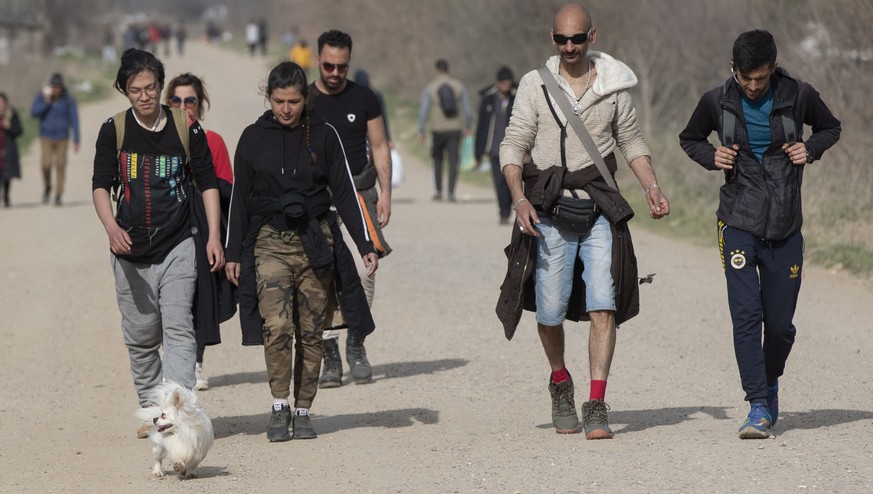 epa08280138 Iranian migrants walk with their dog &#039;Alvin&#039; towards the Greek border near the Pazarkule border gate in Edirne, Turkey, 09 March 2020. Some 10,000 migrants, mostly from Syria, ha ...