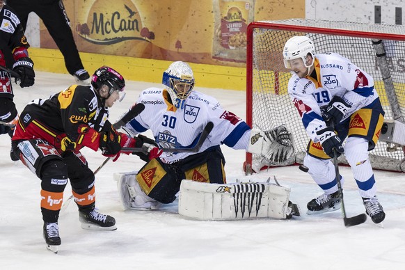 Berns Joel Vermin, links, im Duell mit Zugs Torhueter Leonardo Genoni, Mitte, und Zugs Niklas Hansson im vierten Playoff Viertelfinal Eishockey Spiel der National League zwischen dem SC Bern und dem E ...