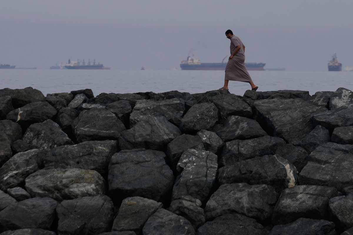 FILE- A man walks along the shore as oil tankers and cargo ships line up in the Strait of Hormuz, seen from Khor Fakkan, United Arab Emirates, March 11, 2026. (AP Photo/Altaf Qadri, File)
Photo Highli ...