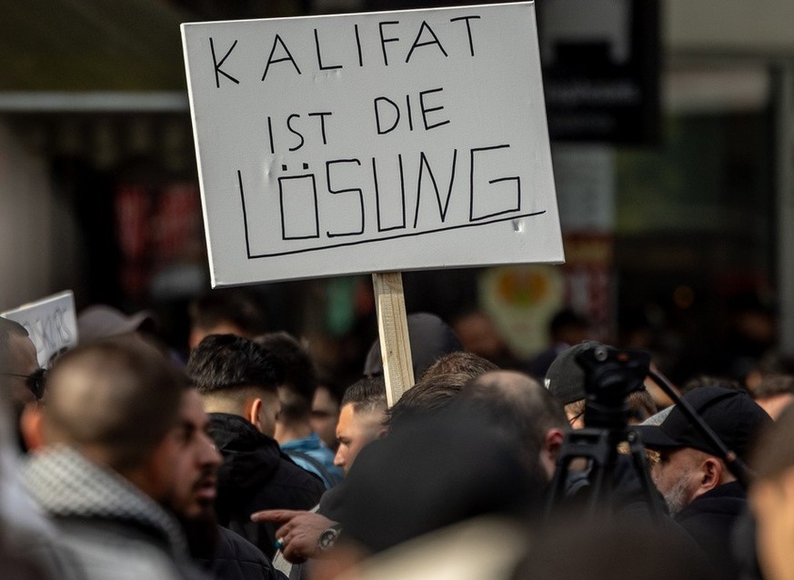 27.04.2024, Hamburg: Teilnehmer einer Islamisten-Demo halten ein Plakat mit der Aufschrift ·Kalifat ist die Lösung· in die Höhe. Foto: Axel Heimken/dpa +++ dpa-Bildfunk +++ (KEYSTONE/DPA/Axel Heimken)