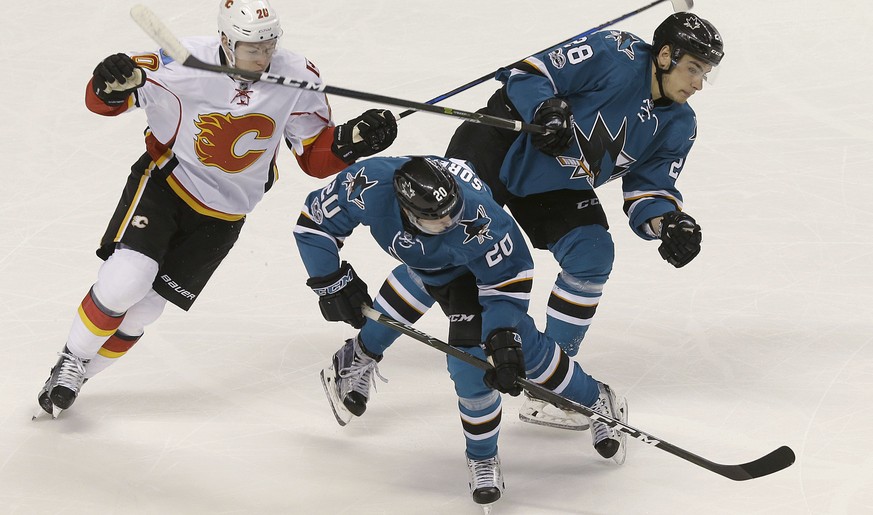 San Jose Sharks right wing Marcus Sorensen, from Sweden, center, tries to control the puck in front of right wing Timo Meier (28), from Switzerland, and Calgary Flames center Curtis Lazar, left, durin ...