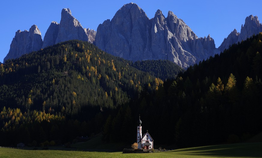 The sun sets at the St. Johann chapel and the Dolomites mountains in St. Maddalena, St. Magdalena, Val di Funes (Villnoess), in northern Italian province of South Tyrol, Italy, Thursday, Oct. 28, 2021 ...