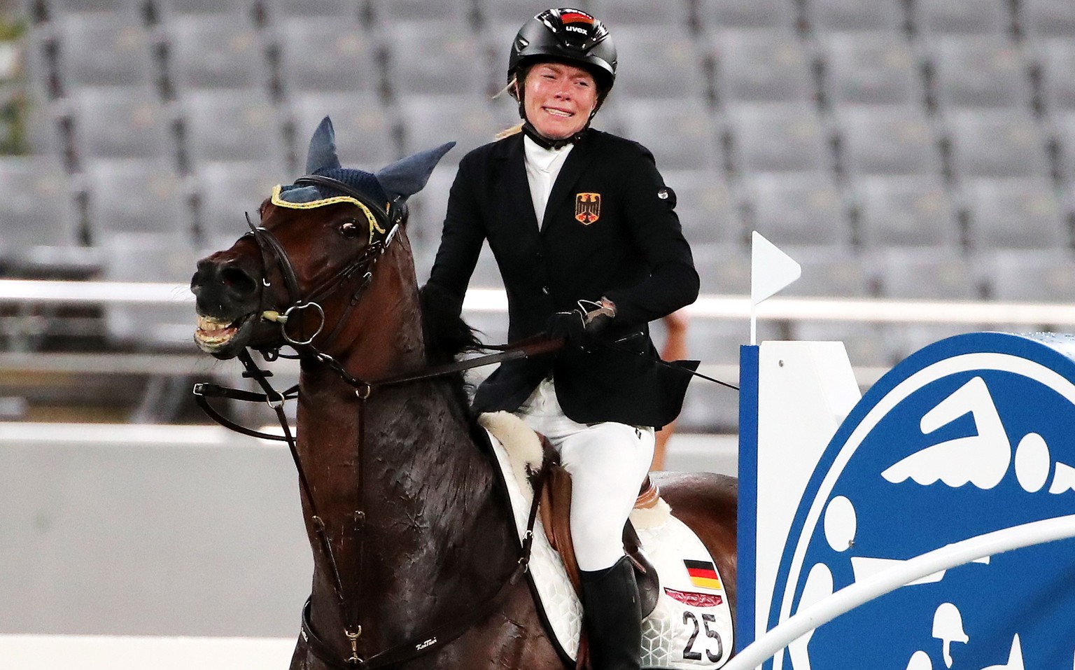 epa09400054 Annika Schleu of Germany on Saint Boy after hitting an obstacle as they compete in the Show Jumping portion of the Modern Pentathlon event at the Tokyo 2020 Olympic Games at the Tokyo Stad ...