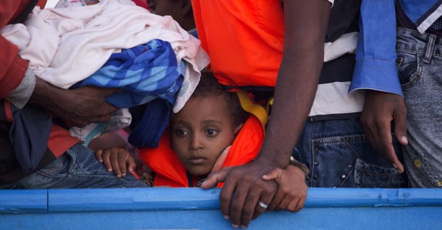 A boy looks on inside a crowded wooden boat carrying more than seven hundred migrants before being rescued, during a rescue operation in the Mediterranean sea, about 13 miles north of Sabratha, Libya, ...