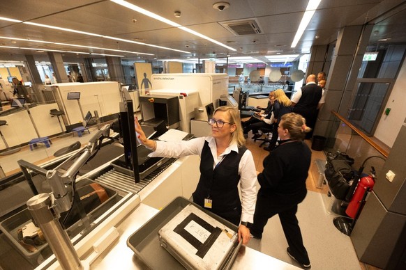 12.10.2023, Hamburg: Neue Gepäckscanner und automatische Personenkontrollen sollen lange Warteschlangen am Hamburg Airport Helmut Schmidt vermeiden. Sicherheitspersonal wird am neuen CT-Gepäckscanner  ...