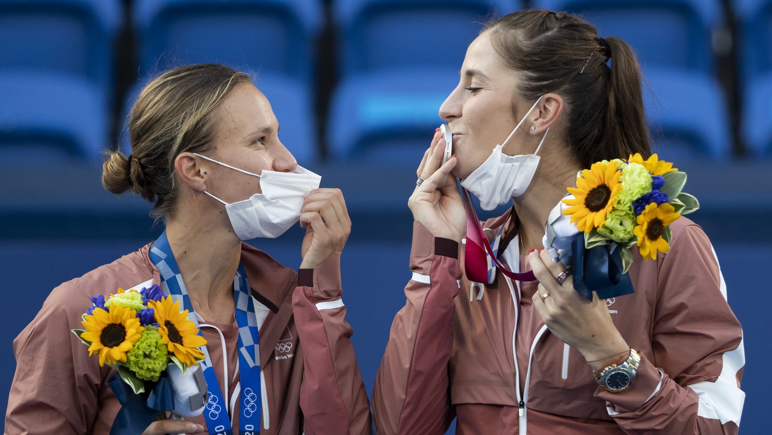 Switzerland&#039;s Belinda Bencic, right, kisses her silver medal next to teammate Viktorija Golubic on the podium after the women&#039;s tennis doubles gold medal match against Barbora Krejcikova and ...