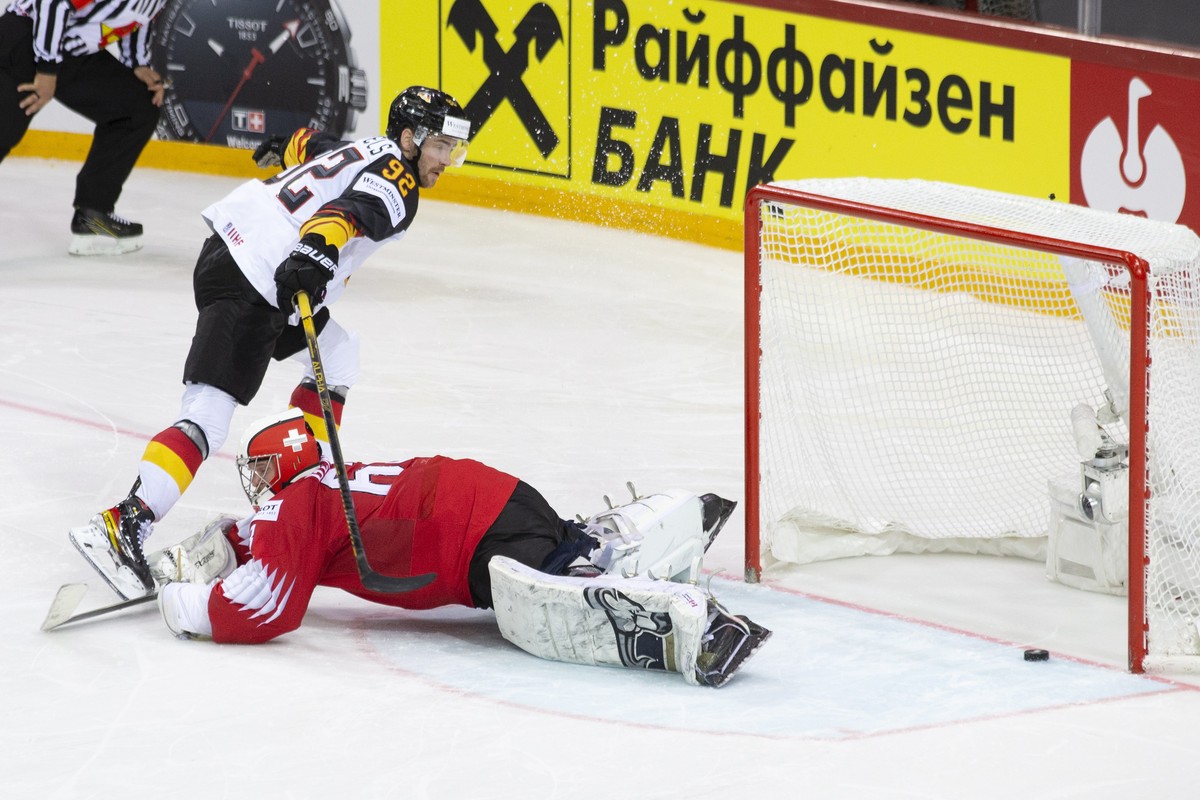 epa09245537 Germany's Marcel Noebels (L) scores the decisive penalty against Swiss goalie Leonardo Genoni (R) during the shootout of the IIHF Ice Hockey World Championship 2021 quarter final game ...