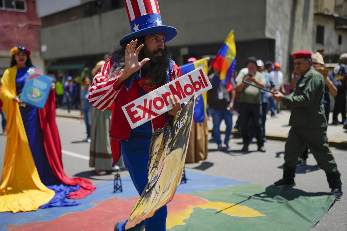 A man dressed as the U.S. character Uncle Sam holds an Exxon oil company sign during a pro-government march coined "Take back the Esequibo," the name of a disputed area with Guyana, in Carac ...