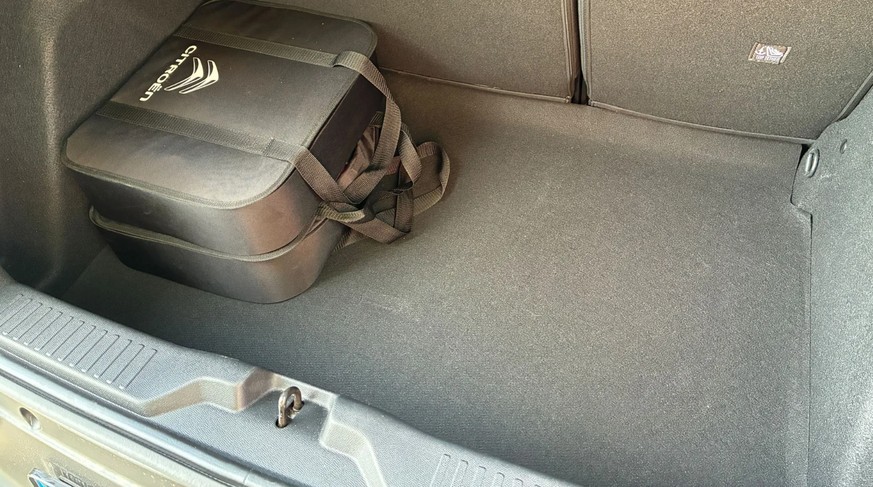 Kofferraum des Citroën ë-c3: Hohe innere Ladekante, etwas dünner Teppich. In den Taschen befinden sich das Ladekabel für das Wechselstrom-Laden und ein weiteres Kabel zum Anschliessen an die Haushalts ...