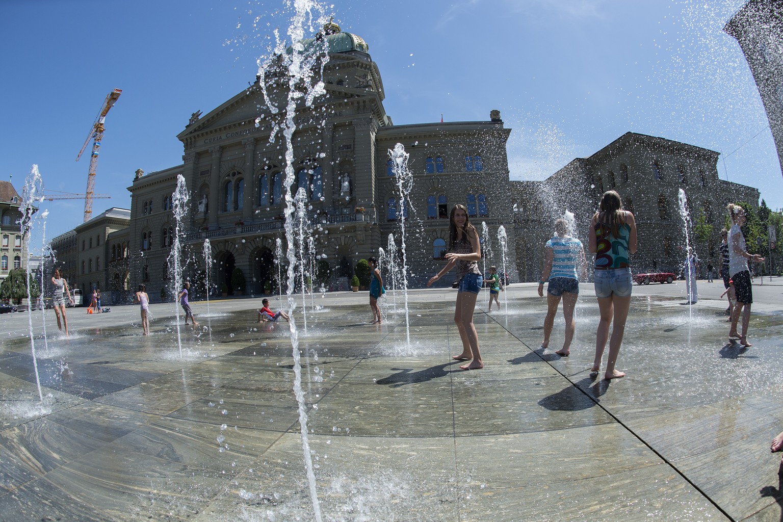 Kinder und Jungendliche vergnuegen sich am Wasserspiel auf dem Bundesplatz am Mittwoch, 11. Juni 2014, in Bern. (KEYSTONE/Marcel Bieri)