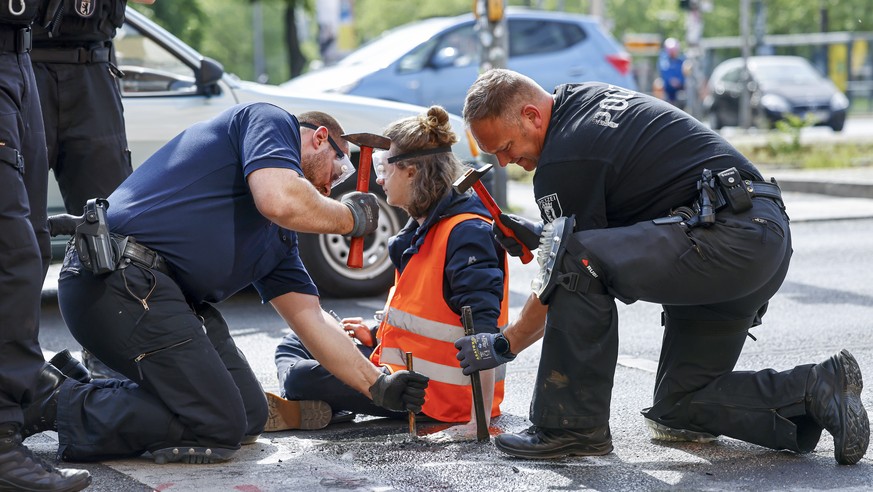epa10645575 Police officers work to free a Letzte Generation (Last Generation) climate activist after he glued himself to the asphalt during a climate protest in Berlin, Germany, 22 May 2023. The acti ...