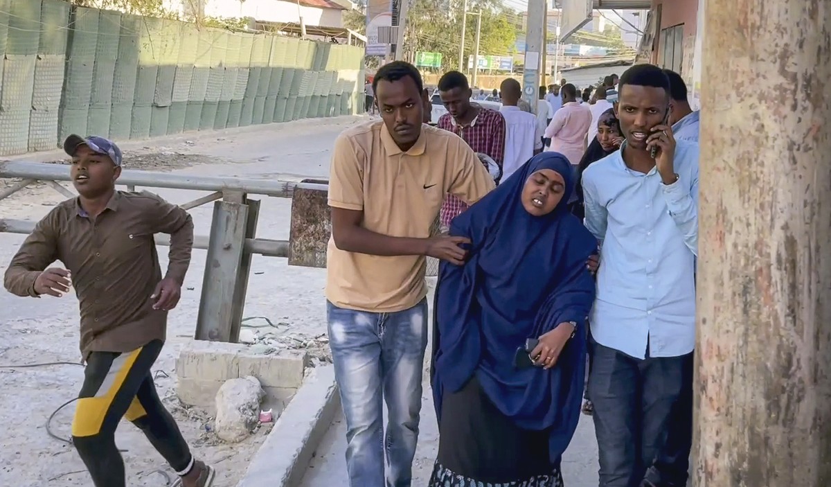 In this image made from video, people flee from the area as gunshots are heard, on a street near the Afrik hotel in the capital Mogadishu, Somalia Sunday, Jan. 31, 2021. The hotel in Somalia's ca ...