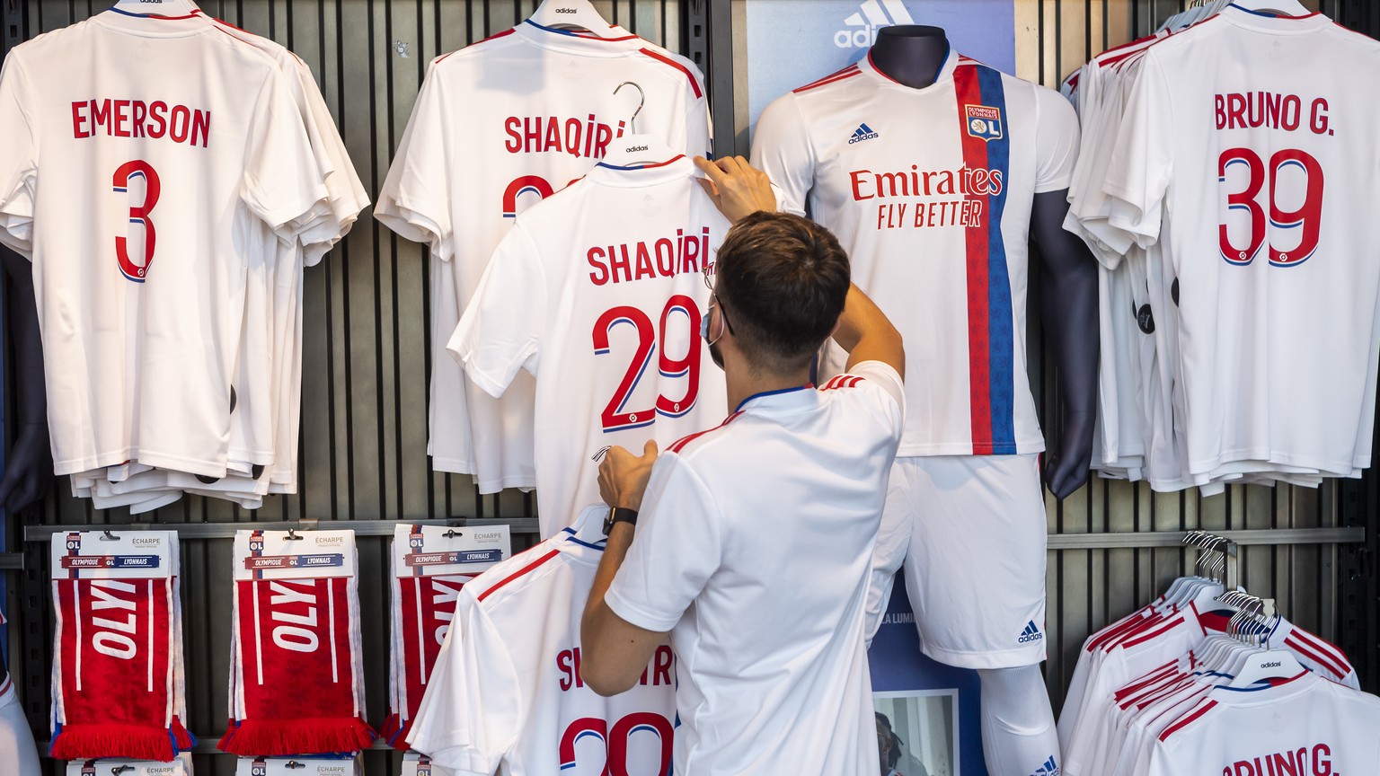 A store employee hangs the Olympique Lyonnais jersey on the store shelf of Switzerland soccer player Xherdan Shaqiri at the OL Store, in Decines-Charpieu near Lyon, France, Wednesday, August 25, 2021. ...