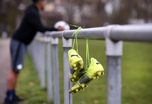 Amateurfussball: Fussball - Ein Junge mit Fussballschuhen in der Hand steht auf einem Sportplatz . *** Football A boy with football boots in hand stands on a sports field