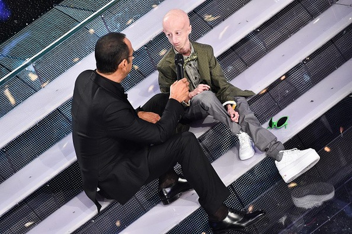 Italian show host Carlo Conti (L) speaks with Italian student Sammy Basso, who suffers from Hutchinson-Gilford Progeria Syndrome attend the fourth night of 65th Festival di Sanremo on February 13, 201 ...