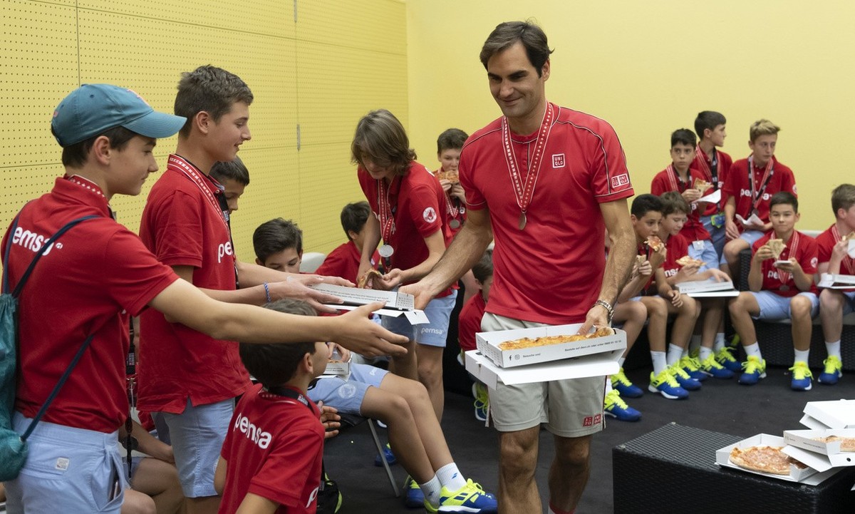Switzerland's Roger Federer eats pizza with the ball kids after winning his tenth title at the Swiss Indoors tennis tournament at the St. Jakobshalle in Basel, Switzerland, on Sunday October 27,  ...