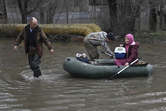 A man pulls a rubber boat carrying a woman with a cat through a flooded street after part of a dam burst, in Orsk, Russia. State media say Russia&#039;s government has declared the situation in flood- ...