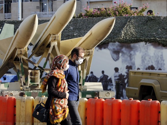 epa09487894 An Iranian couple walk next to short-range missiles in a street exhibition by Iran&#039;s army and paramilitary Revolutionary Guard celebrating &#039;Defence Week&#039; marking the 41th an ...