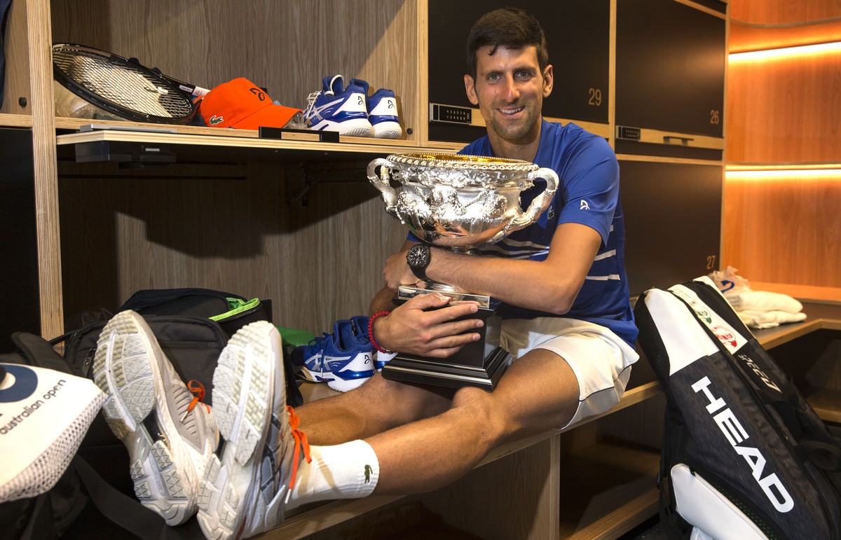 epa07324779 A handout photo made available by TENNIS AUSTRALIA shows Novak Djokovic of Serbia posing with the winner's trophy, the Norman Brookes Challenge Cup, in the mens locker room after defe ...