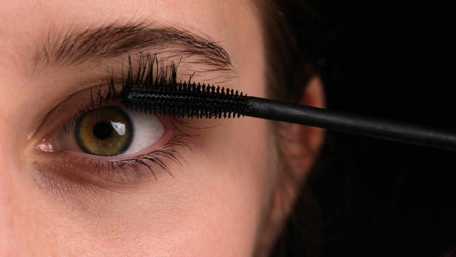 Eine Frau trägt Mascara auf.