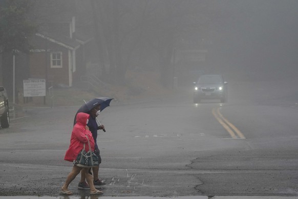 Two people cross the road as wind and rain pummel the area Friday, Sept. 9, 2022, in Julian, Calif. A tropical storm nearing Southern California has brought fierce mountain winds, high humidity, rain  ...