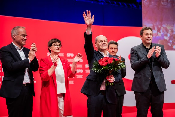 epa11818597 German Chancellor Olaf Scholz holds a bouquet of flowers as he reacts to being confirmed as candidate for the Chancellor in the February election, next to Social Democratic Party (SPD) Sec ...