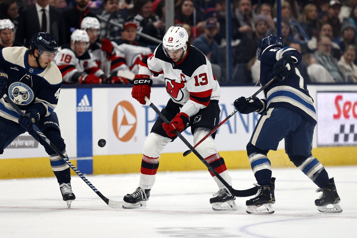 New Jersey Devils forward Nico Hischier, center, works for the puck between Columbus Blue Jackets forwards Cole Sillinger, left, and Justin Danforth, right, during the second period an NHL hockey game ...