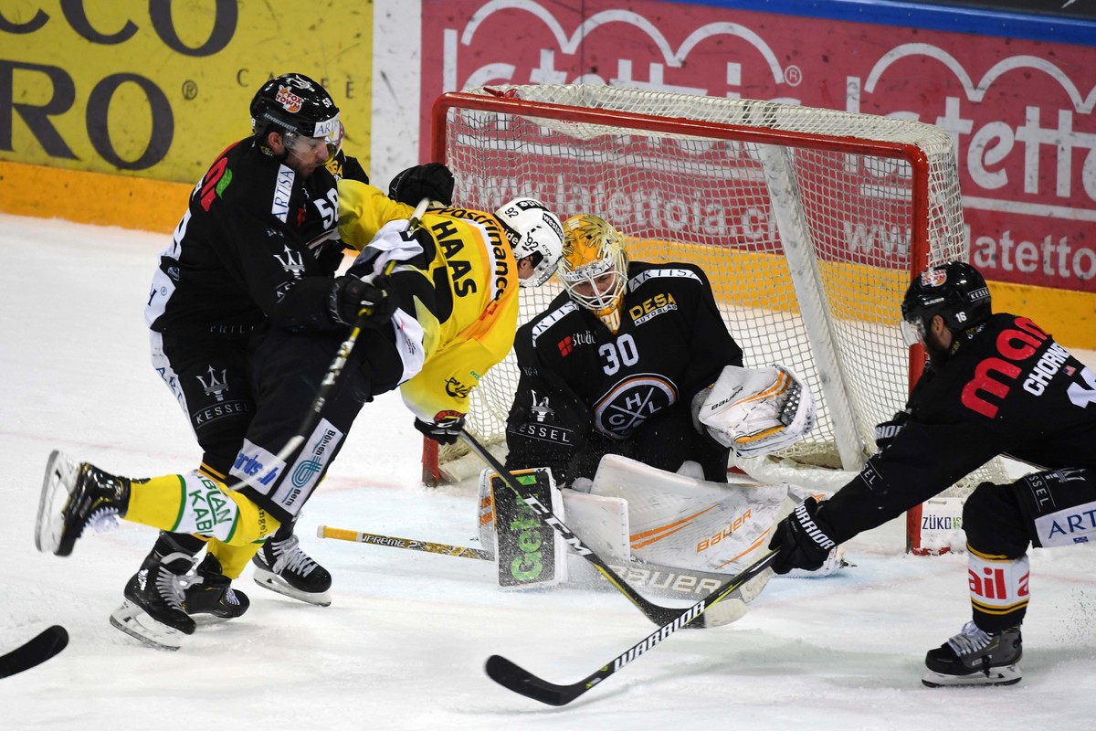 Lugano's player Romain Loeffel, Bern's player Gaetan Haas, Lugano's goalkeeper Elvis Merzlikins and Lugano's player Taylor Chorney, from left, during the regular season game of Nat ...