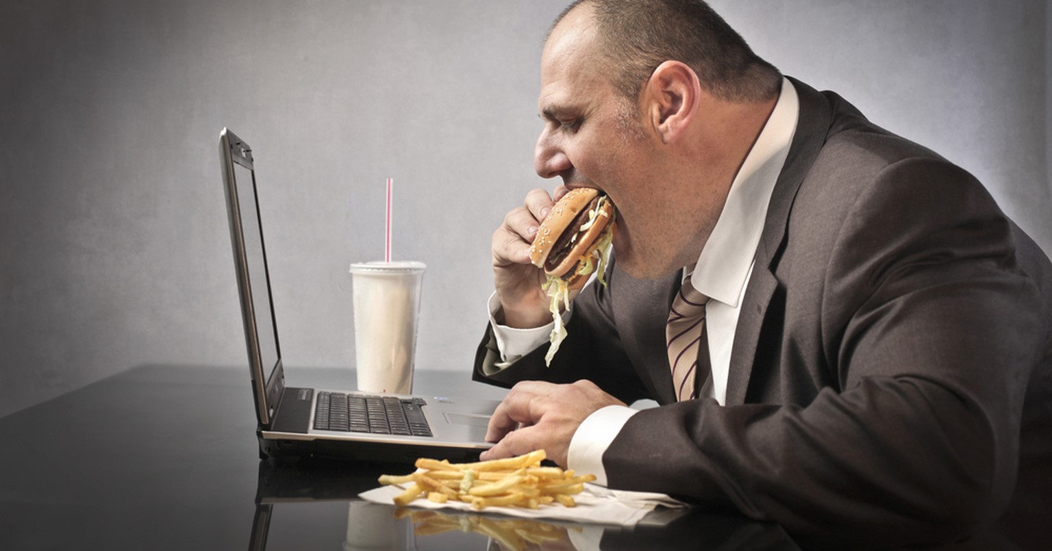 Übergewicht, Adipositas, dicker Mann, Fast Food im Büro, Essen vor dem Bildschirm (Symbolbild)