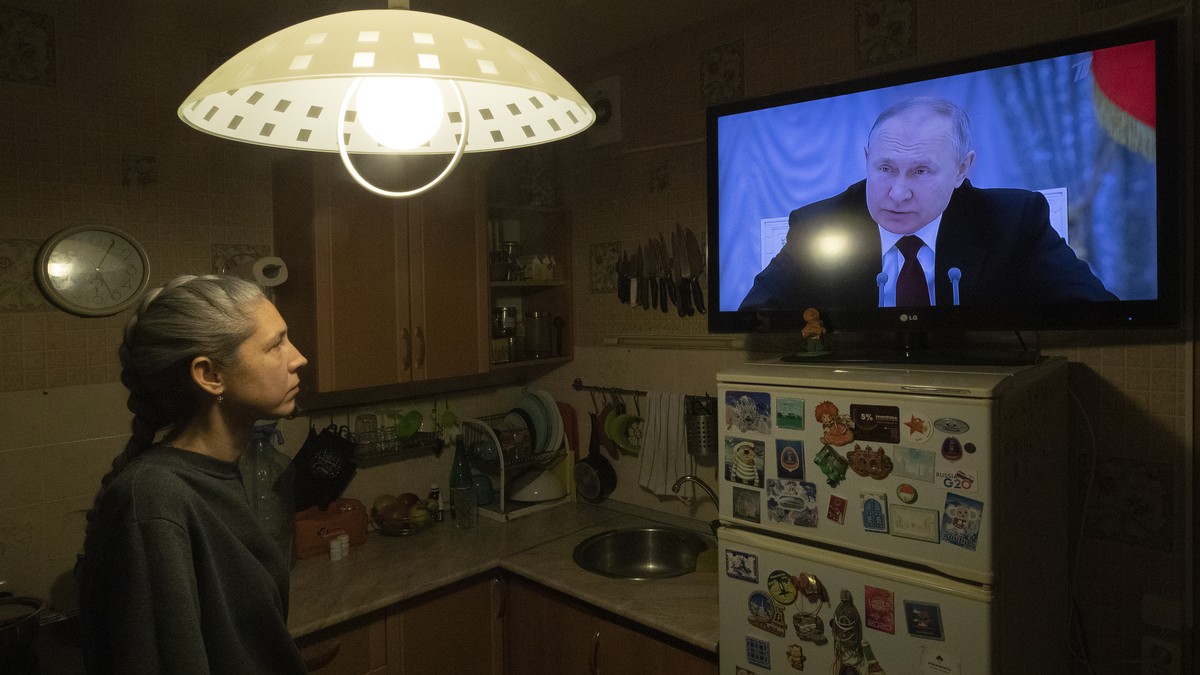 epaselect epa09775854 A woman watches TV with Russian President Putin speaking during a broadcast of a meeting of the National Security Council on the recognition of the self-proclaimed Donetsk People ...