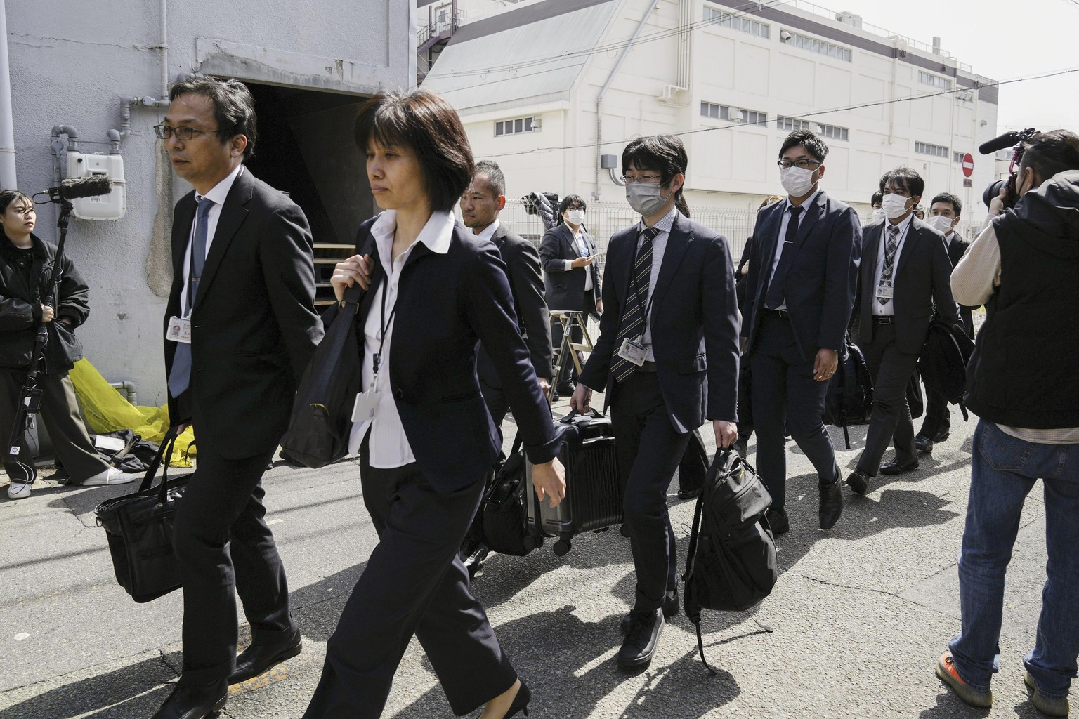 Japan&#039;s health ministry officials walk towards the Osaka plant of Kobayashi Pharmaceutical Co. to conduct an on-site inspection in Osaka, western Japan, Saturday, March 30, 2024. Japanese governm ...